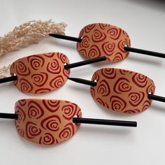 four wooden hair pins with red designs on them