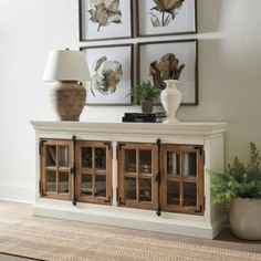 a living room with two framed pictures on the wall and a white entertainment center in front of it