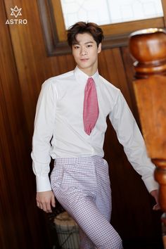 a young man in a white shirt and red tie standing next to a wooden staircase