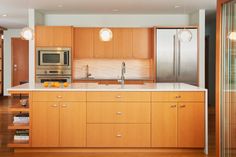 a kitchen with wooden cabinets and stainless steel appliances in the center, along with hardwood flooring