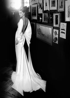 a black and white photo of a woman standing in front of pictures on the wall