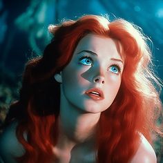 a woman with long red hair and blue eyes is staring at something in the distance