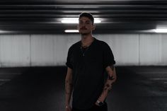 a man standing in the middle of an empty parking garage with his hand on his hip