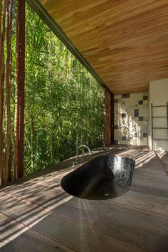 an outdoor bathtub in the middle of a wood floored area with bamboo trees