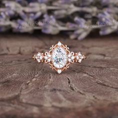 a close up of a ring on a piece of wood with flowers in the background