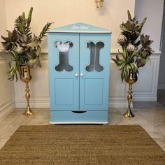 a blue cabinet sitting in the middle of a living room next to two potted plants