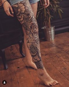 a woman's legs with tattoos on them and flowers in the middle of her leg