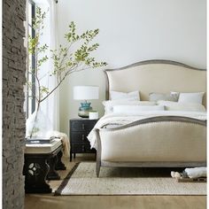 a bedroom with a bed, nightstands and a plant in the corner on the floor