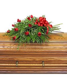 a bouquet of red and white flowers on top of a wooden casket