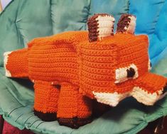 an orange knitted animal laying on top of a green chair