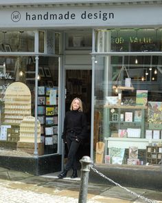 a woman standing in the doorway of a store with lots of books on display behind her