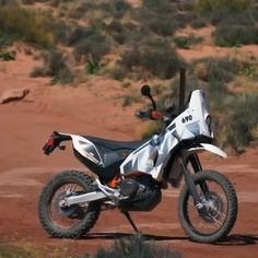 a white dirt bike parked on top of a dirt field