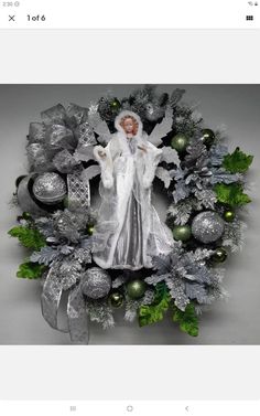 a christmas wreath with an angel surrounded by silver and green ornaments on top of it