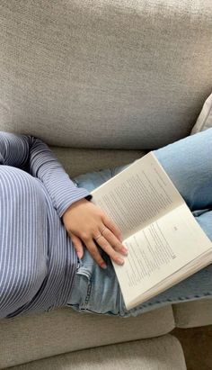 a woman sitting on a couch reading a book