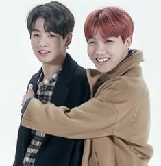 two young men are hugging each other in front of a white background and one has red hair