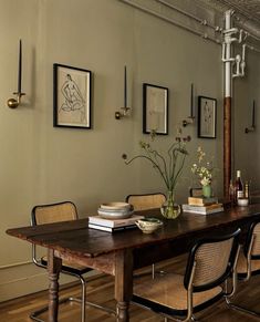 a dining room table with chairs and pictures on the wall above it in an industrial style