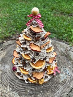 a christmas tree made out of old newspapers and dried oranges is sitting on a stump in the grass