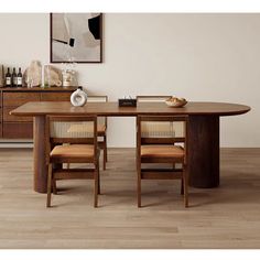 a wooden table with chairs around it in front of a white wall and wood flooring