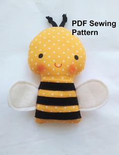 a yellow and black stuffed bee with polka dots on it's wings, sitting on a white surface