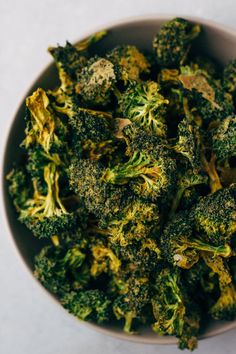 a white bowl filled with broccoli florets on top of a table