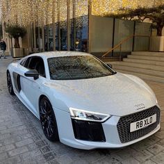 a white car parked in front of a building with lights on the side of it