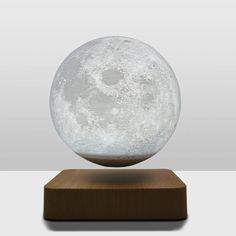 the moon lamp is sitting on top of a wooden base and it's glowing