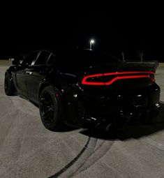 a black sports car parked in the parking lot at night with its tail lights on