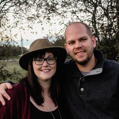 a man and woman standing next to each other with trees in the back ground behind them