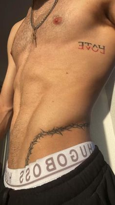 a shirtless man with barbed wire around his waist and the word love tattooed on his chest