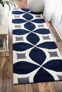 a blue and white rug on the floor in a living room with wood floors, potted plant and window