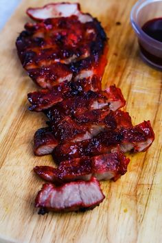 sliced bacon on a cutting board next to a bowl of ketchup and sauce