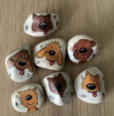 painted rocks with dogs on them sitting on a wooden table next to another set of rocks