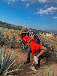 a man and woman standing next to each other in front of an agavena field