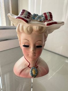 a statue of a woman with a hat on top of it's head, sitting on a table