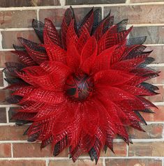 a red and black wreath hanging on a brick wall