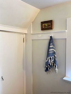 a towel hanging on the wall next to a window with a framed picture above it