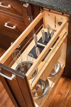 an open drawer in a kitchen with stainless steel utensils