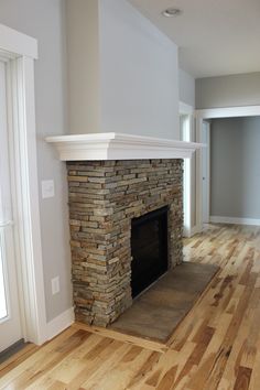 an empty living room with a fireplace and hard wood floors