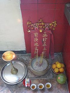 a table with bowls and plates on it next to a vase filled with flowers, lemons and water