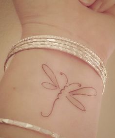 a woman's arm with a tattoo on it that has a dragonfly on it