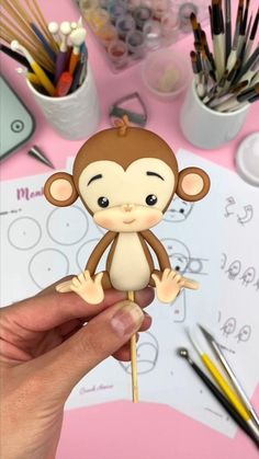 a person holding a small monkey on a stick in front of some pens and pencils