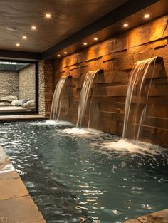 an indoor swimming pool with water running down the side and waterfall cascading on both sides