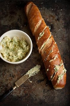 a long loaf of bread sitting next to a bowl of dip