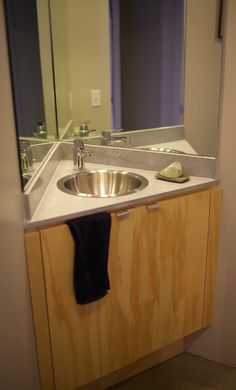 a bathroom sink sitting under a mirror next to a wooden cabinet with a towel hanging on it