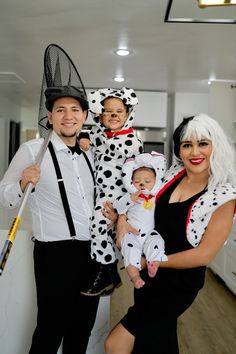 three people dressed up as dalmatian and one is holding a baby in his arms