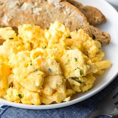 scrambled eggs on a white plate with bread