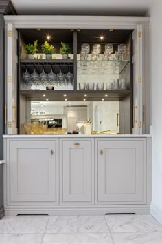 a kitchen with white cabinets and shelves filled with glassware on the top shelfs