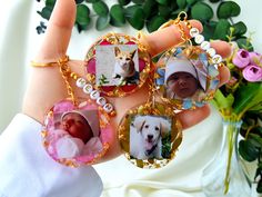 a hand holding four different pictures of dogs on it's bracelets, with flowers in the background