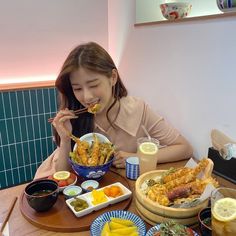 a woman sitting at a table eating food with chopsticks in front of her