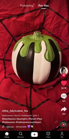 a black and white pumpkin sitting on top of a red bed sheet with the caption, following for you